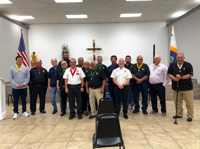 About twenty members of Council 10562 standing together beneath a crucifix