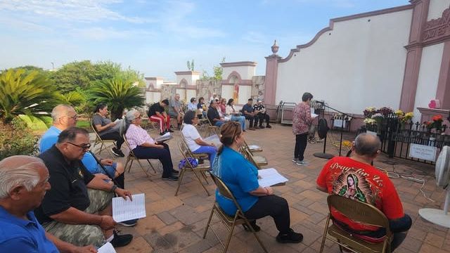 Parishioners gathered in folding chairs on a church courtyard